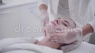 医生从病人脸上取出凝胶，涂上治疗霜。 <strong>抗痘</strong>光疗.. 美丽的女人